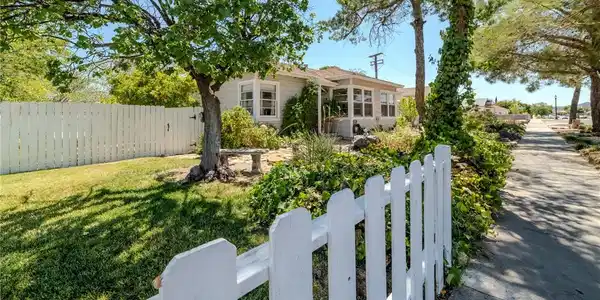 Image 3: A classic picket fence and lush landscaping welcom