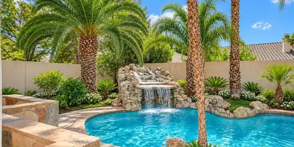 Image 3: Lush palm trees and a cascading stone waterfall fr