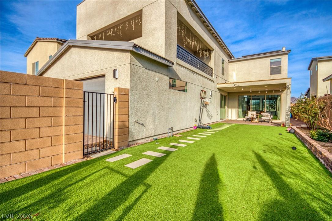 Image 2: Rear view of property featuring a gate, stucco sid