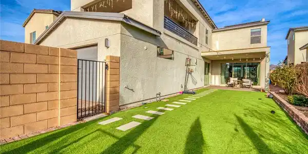 Image 2: Rear view of property featuring a gate, stucco sid