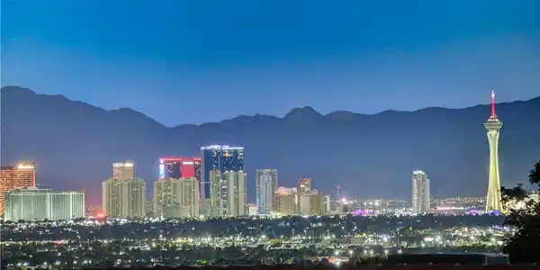 Image 3: City lights glow against a mountain backdrop under