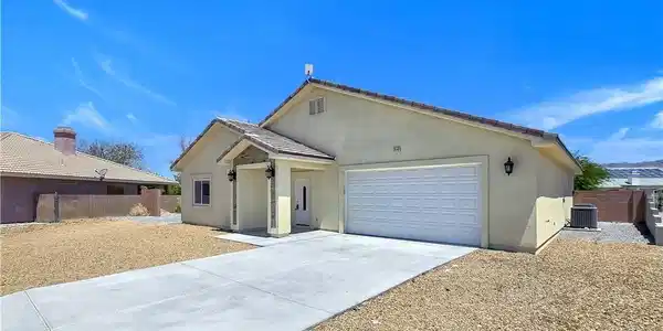 Image 2: A well-maintained stucco home offers a concrete dr