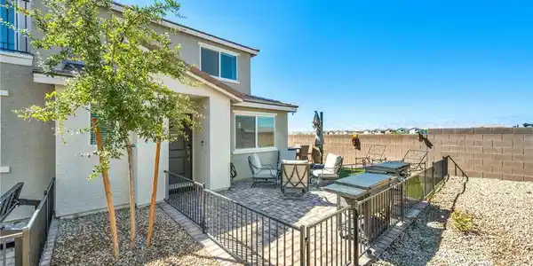 Image 2: A spacious paved frontyard patio sits enclosed by