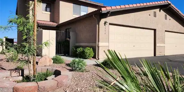 Image 2: A well-maintained stucco home with a tile roof and