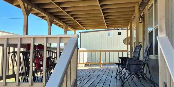 Image 4: Steps ascend to a spacious covered wooden deck per