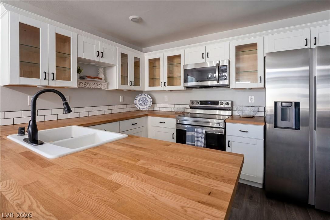 Image 4: White cabinetry, butcher block countertops, and su
