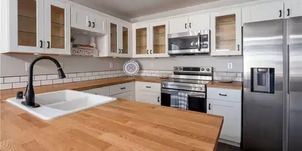 Image 4: White cabinetry, butcher block countertops, and su
