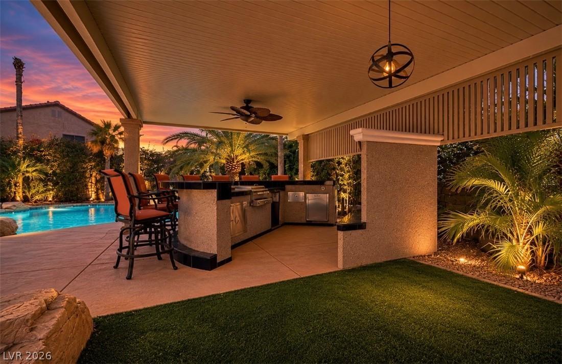 Image 4: An illuminated outdoor kitchen with a covered pati