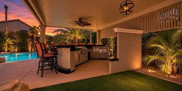 Image 4: An illuminated outdoor kitchen with a covered pati