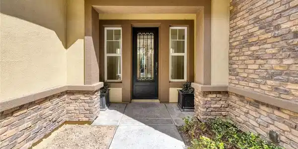 Image 3: Stone accents and a decorative glass door create a