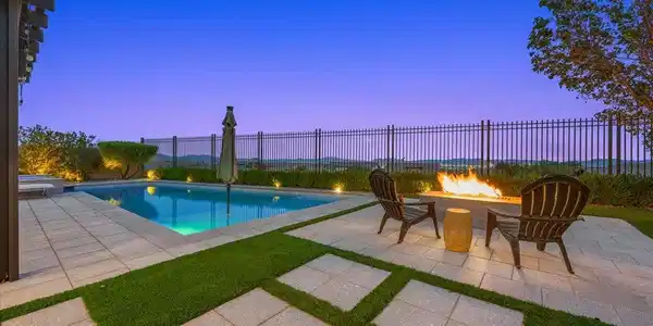 Image 2: An inviting stone patio surrounds the sparkling sw