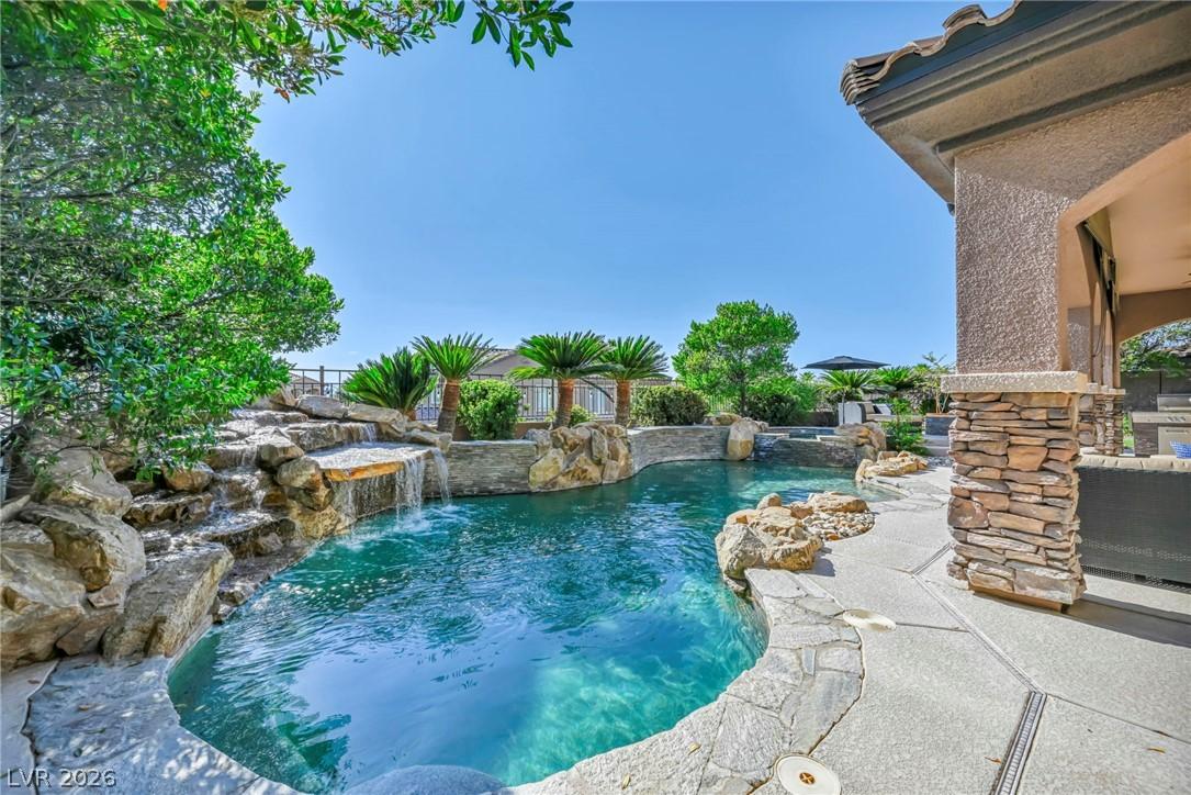 Image 4: A lagoon-style pool with natural rock waterfalls c