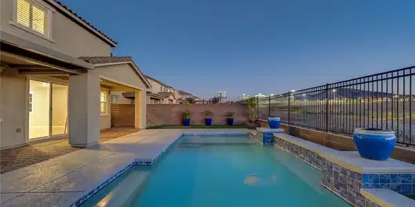 Image 4: A sparkling in-ground pool is framed by a paved pa