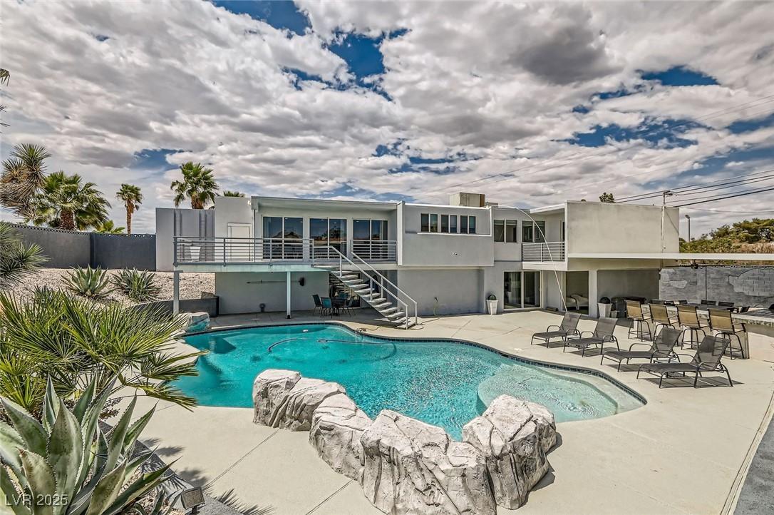 Image 2: View of pool featuring stairs, a patio, and a bar