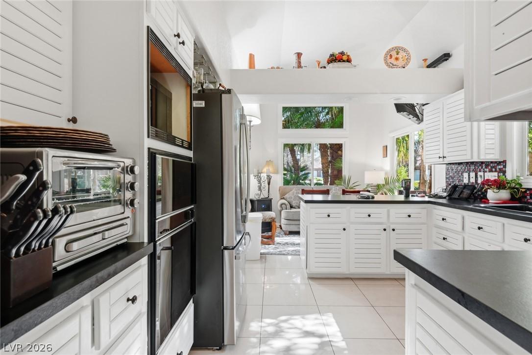 Image 2: White cabinetry with black countertops creates a s