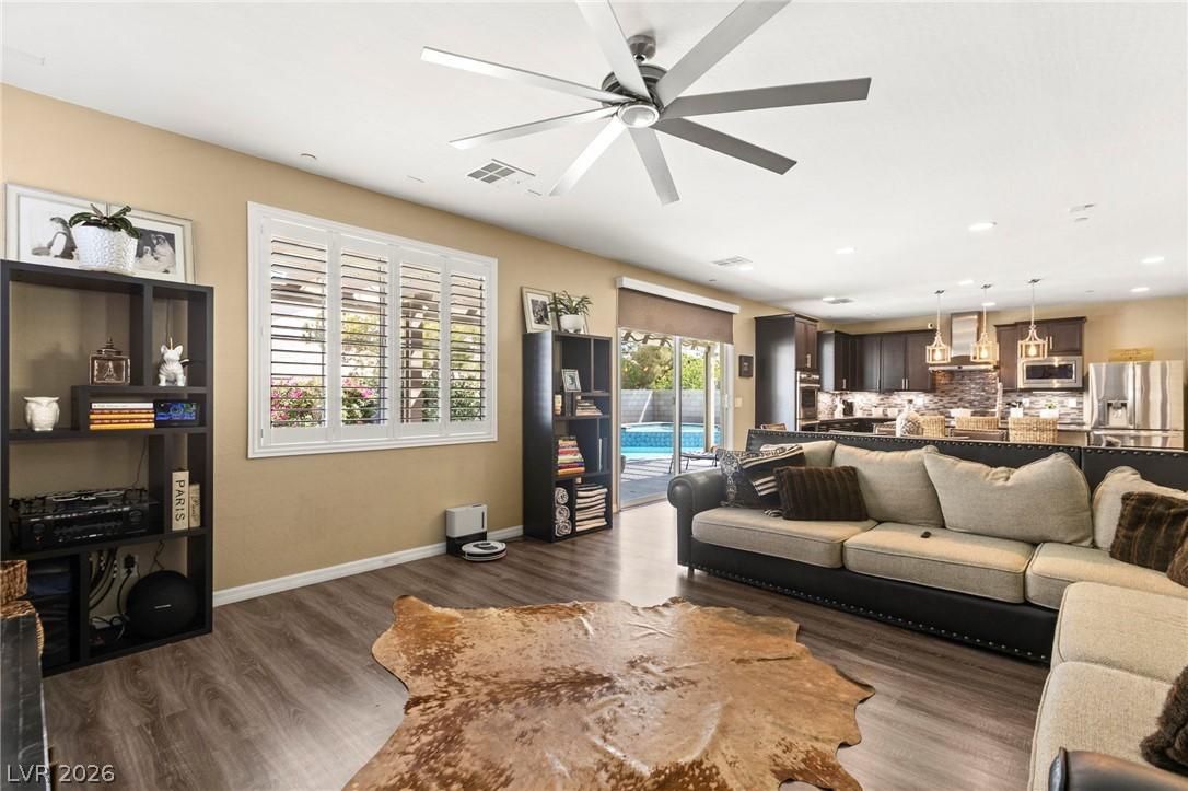 Image 2: A spacious living area with warm wood flooring ope