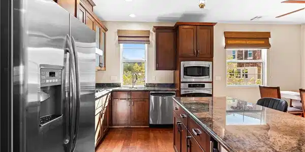 Image 4: A gourmet kitchen boasts granite counters, rich wo