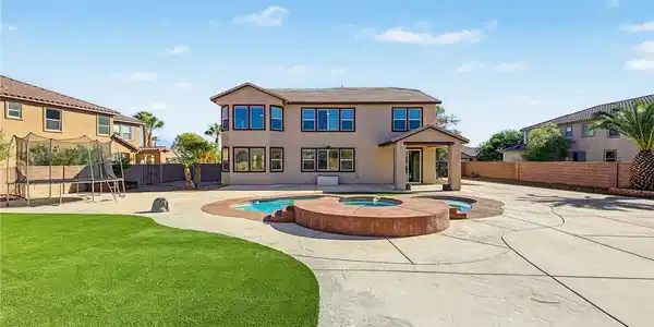 Image 2: An expansive backyard patio features concrete surr
