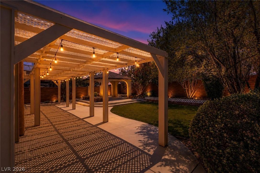 Image 4: Illuminated patio with string lights, a manicured