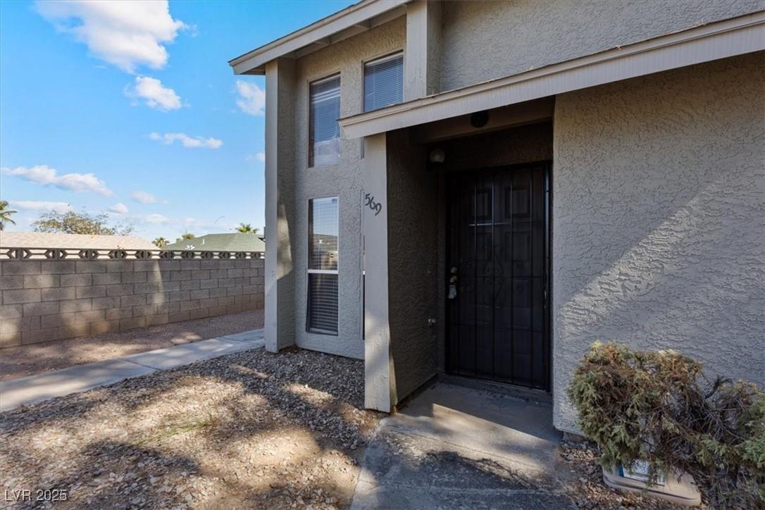 Image 2: View of exterior entry featuring stucco siding