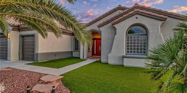 Image 3: An inviting entry to this stucco home, framed by l