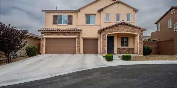 Image 4: Two-story home with a stone-accented facade and tw