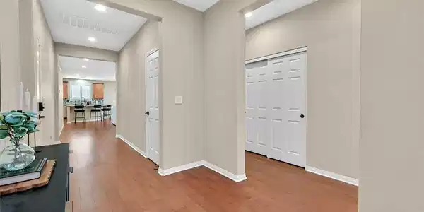 Image 4: A warm wooden floor leads into a bright, open livi