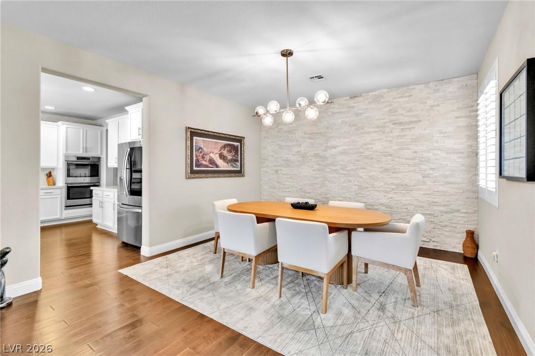 Image 4: A well-lit dining area featuring rich hardwood flo