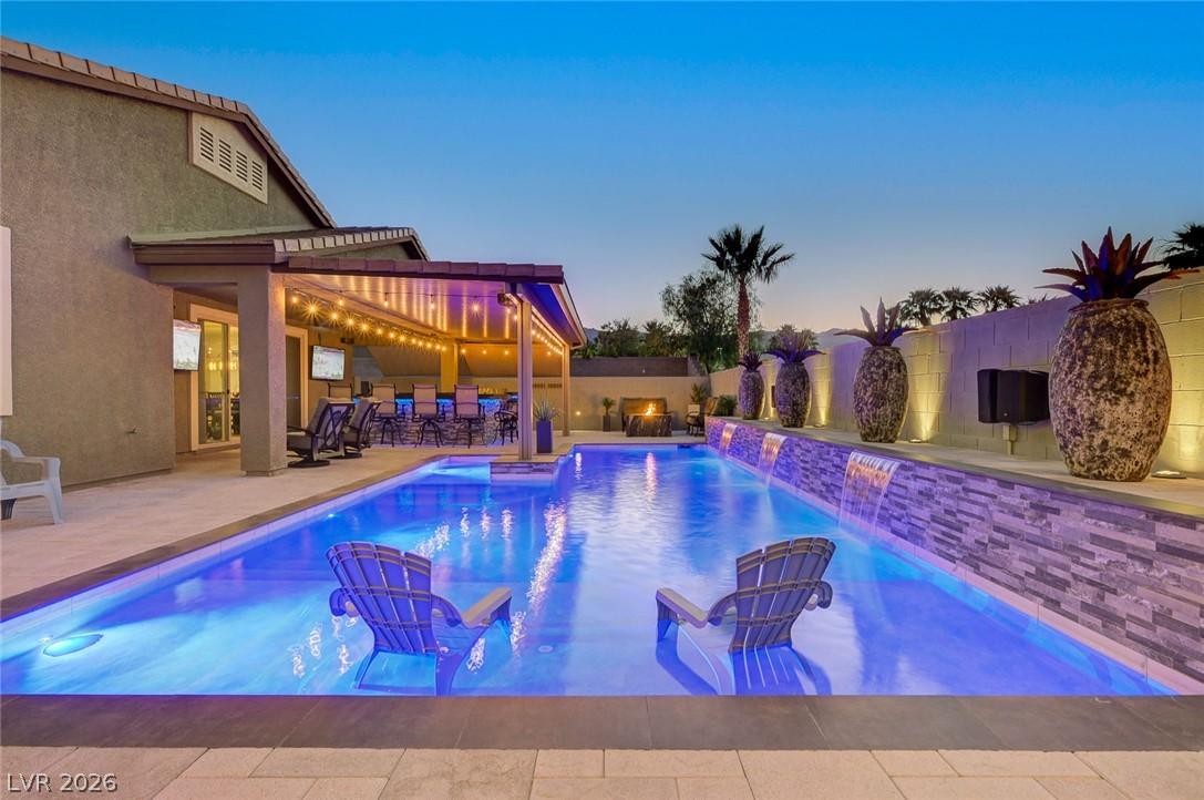 Image 4: An illuminated backyard oasis boasts a sparkling p
