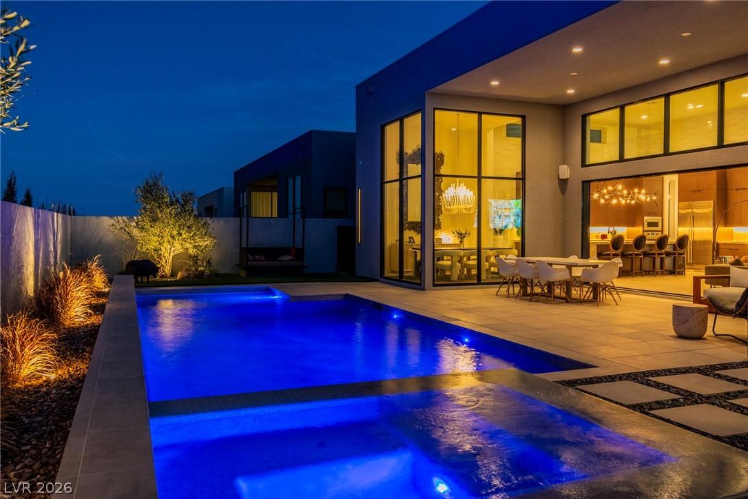 Image 3: An illuminated backyard oasis boasts a pristine po