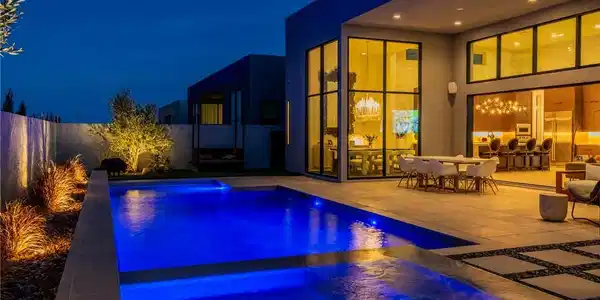 Image 3: An illuminated backyard oasis boasts a pristine po