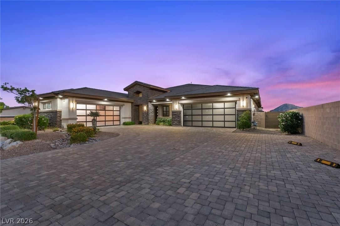 Image 4: A grand paver driveway leads to a modern facade wi