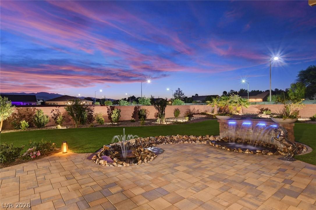 Image 3: An illuminated backyard oasis features a paved pat