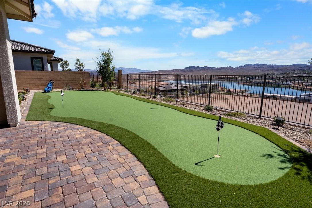 Image 1: Fenced yard featuring a putting area, a mountain v