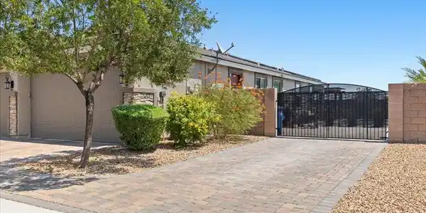 Image 3: A secure, brick-paved driveway leads to a two-car