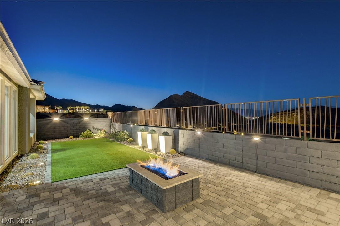 Image 2: An inviting backyard oasis offers a fire pit, pati