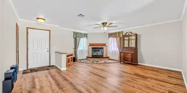 Image 3: Warm wood-look flooring and a brick fireplace crea