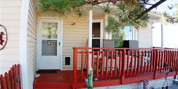 Image 3: A welcoming front porch features vibrant red raili