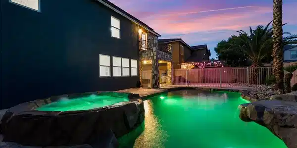 Image 2: An inviting backyard pool oasis features rock acce