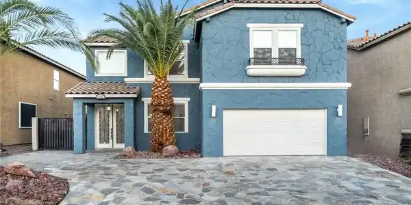 Image 4: A textured stucco exterior and flagstone driveway