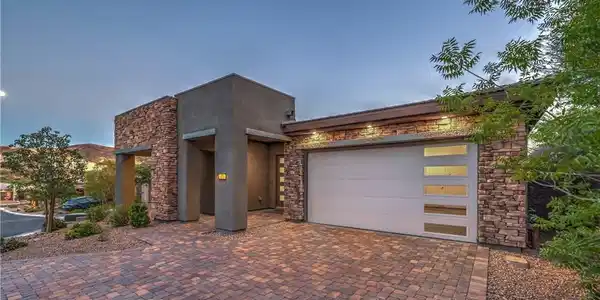 Image 4: A modern facade with stone accents and a paver dri