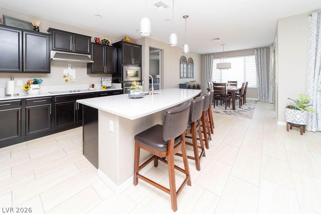 Image 4: An open concept kitchen features sleek dark cabine