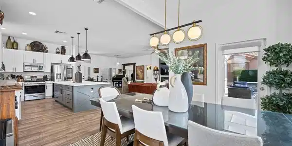 Image 2: An open-concept living space features wood floorin