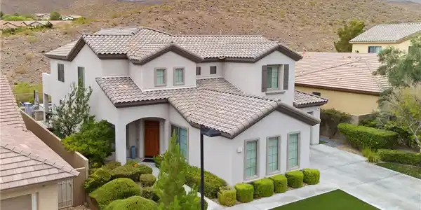 Image 2: A striking stucco residence with a tiled roof sits