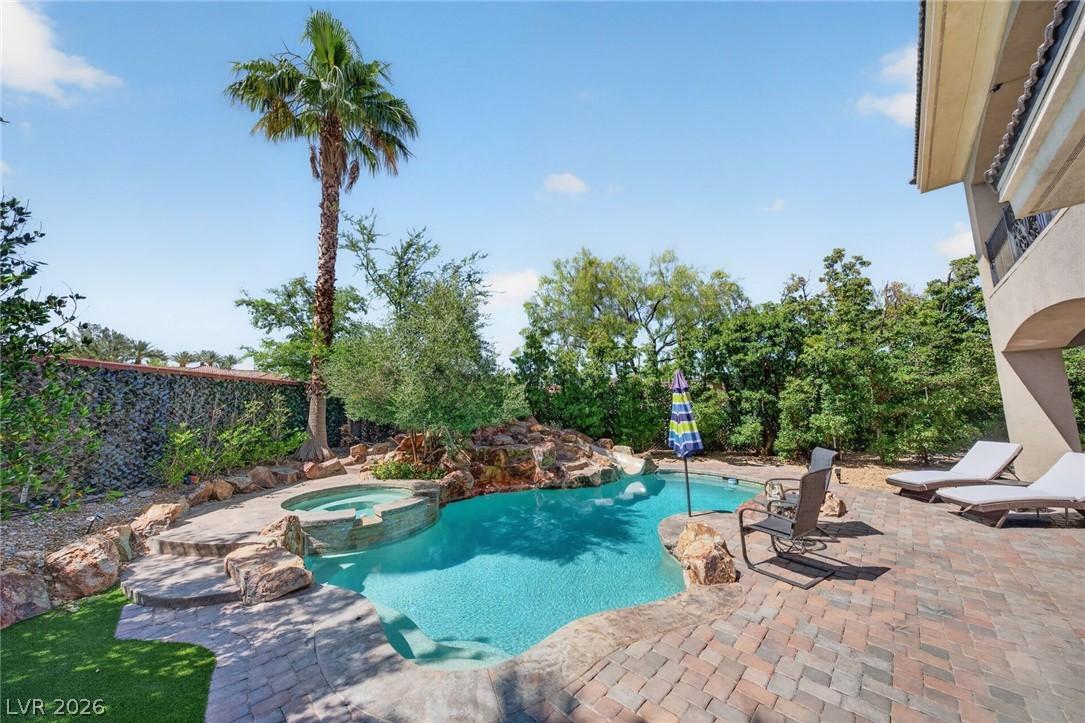 Image 3: A refreshing pool and spa with rock features and l