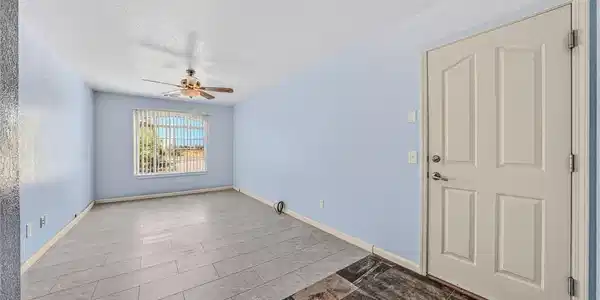 Image 3: A window-filled living area features a ceiling fan
