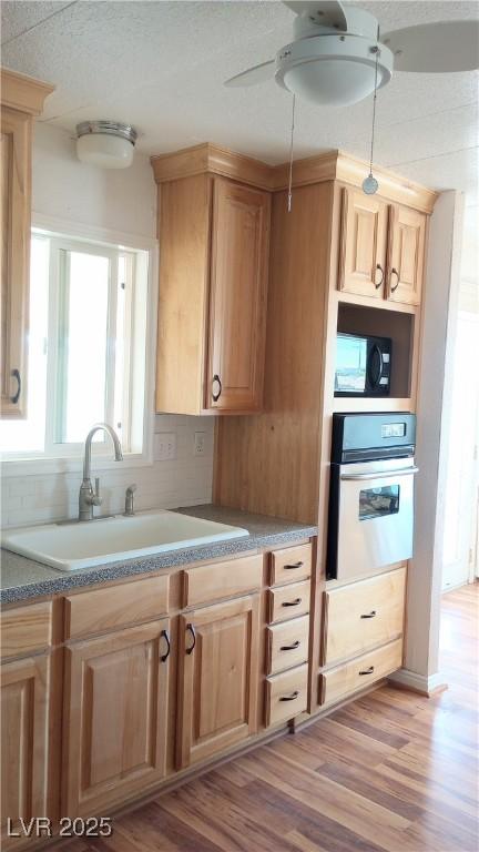 Image 4: Kitchen featuring light brown cabinetry, oven, lig