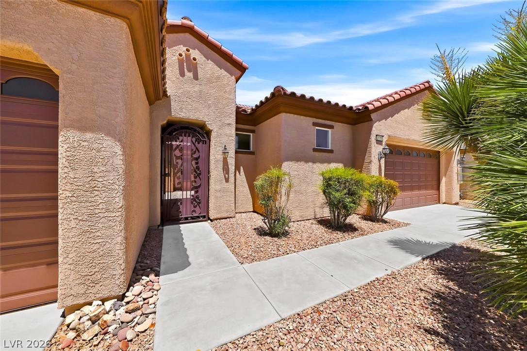 Image 2: An inviting entry gate leads to a warm stucco exte