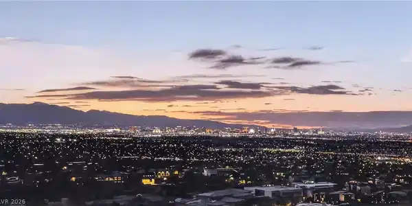 Image 2: City lights stretch towards distant mountains unde