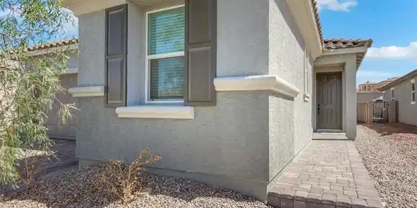 Image 3: Classic stucco exterior and a paved walkway lead t